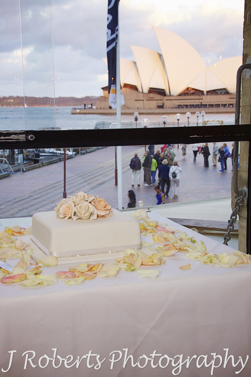 Wedding cake in front of window overlooking the opera house at wolfies grill the rocks - wedding photography sydney
